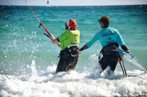 instructeur de kitesurf qui accompagne son élève dans l'eau