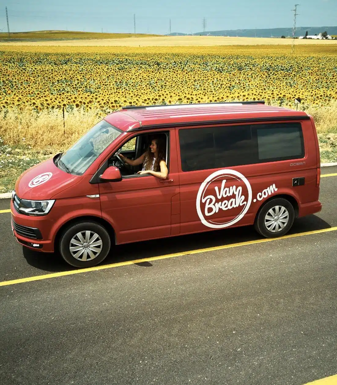 Woman driving a red Campervan VW on a roadtrip