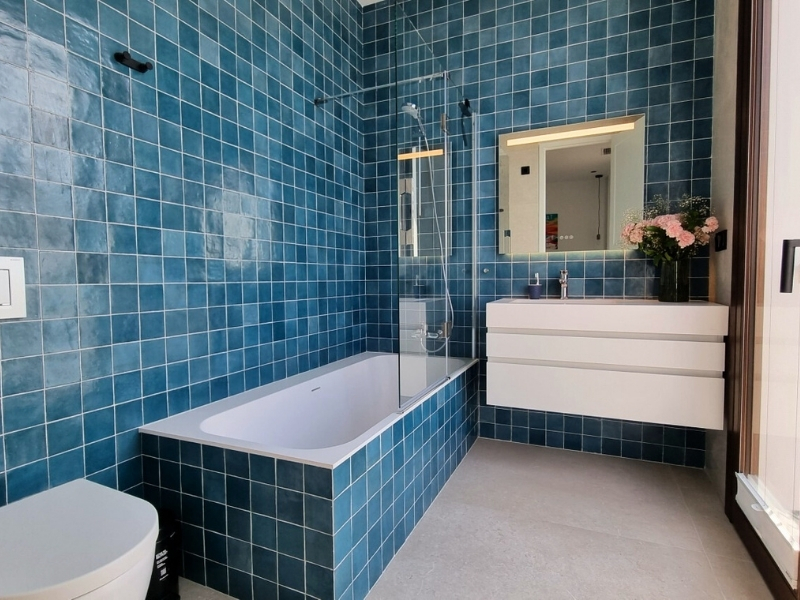 Baño con bañera y habitación con doble cama.