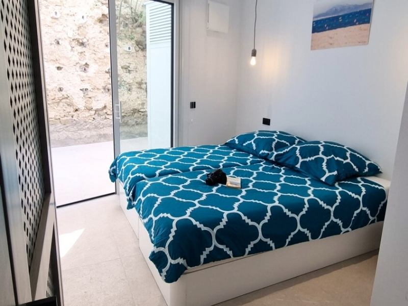Dormitorio doble con terraza y vista a la pared de la muralla del casco antiguo.